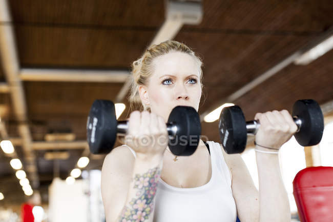 Young woman lifting dumbbells — Stock Photo