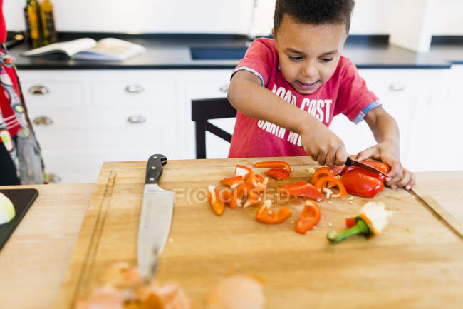 Junge hackt rote Paprika — Stockfoto