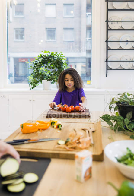 Menina cortando tomates na cozinha — Fotografia de Stock