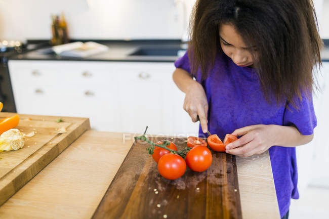 Ragazza affettare pomodori — Foto stock