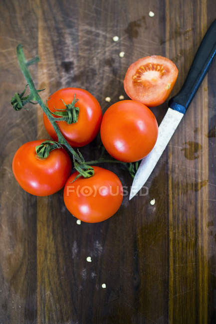 Tomatoes and knife on chopping board — Stock Photo