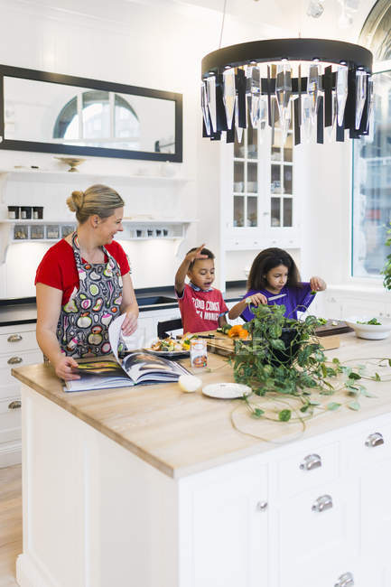 Mother and children cooking food in kitchen — Stock Photo