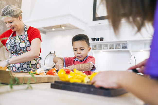 Mother with children chopping vegetables — Stock Photo