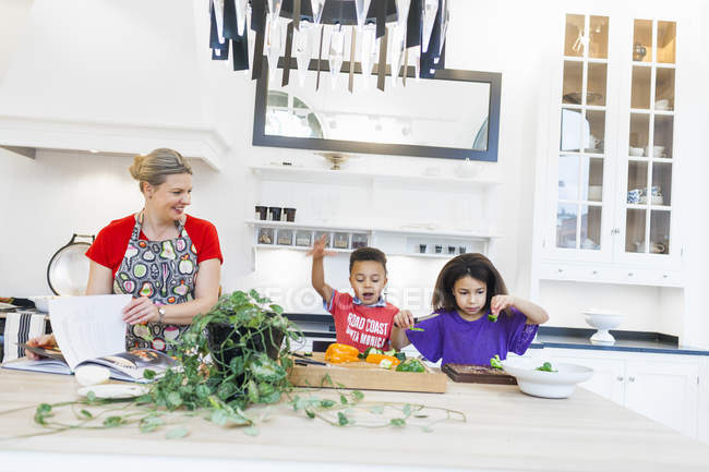 Madre con niños cocinando juntos - foto de stock