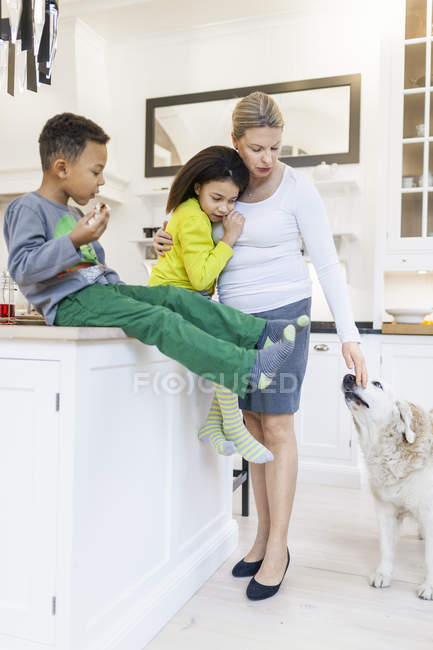 Family standing with dog in kitchen — Stock Photo