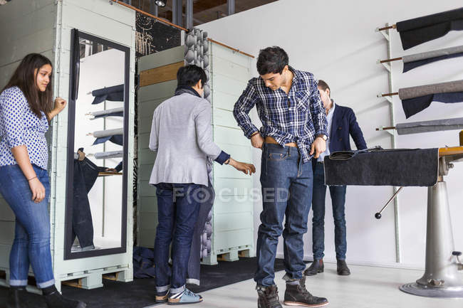 Woman looking at man trying jeans — Stock Photo