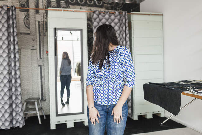 Mujer joven probándose jeans - foto de stock