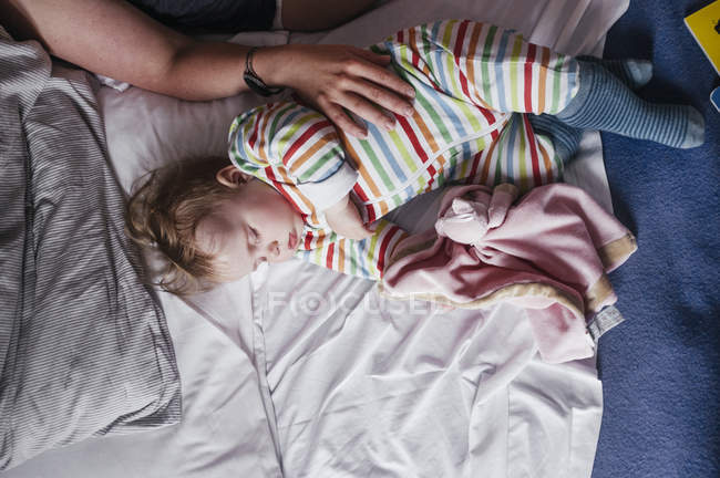 Mujer tocando bebé niña en la cama - foto de stock