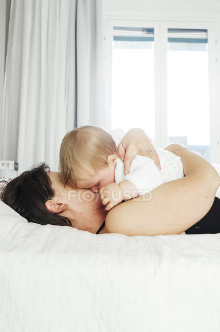 Donna che abbraccia il bambino a letto — Foto stock