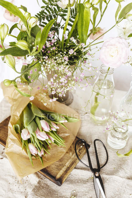 Flores e vasos na mesa sobre fundo branco — Fotografia de Stock