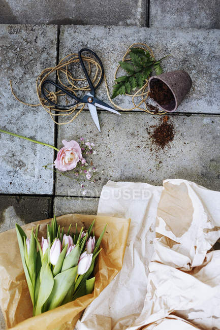 Tulip bouquet with scissors and pot on concrete floor — Stock Photo
