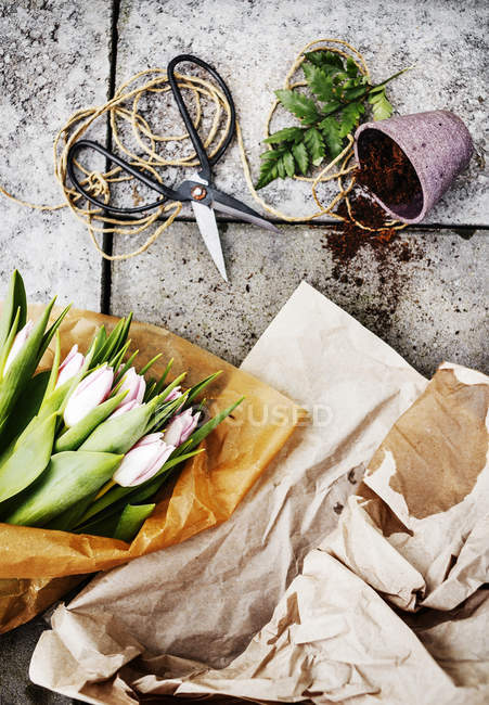 Buquê de tulipa com tesoura e panela no chão de concreto — Fotografia de Stock