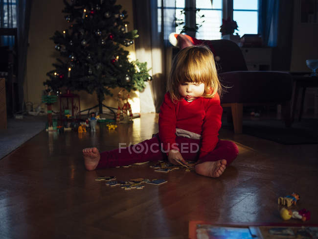 Cute girl solving jigsaw puzzle — Stock Photo