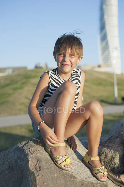 Retrato de niña sentada en la roca - foto de stock
