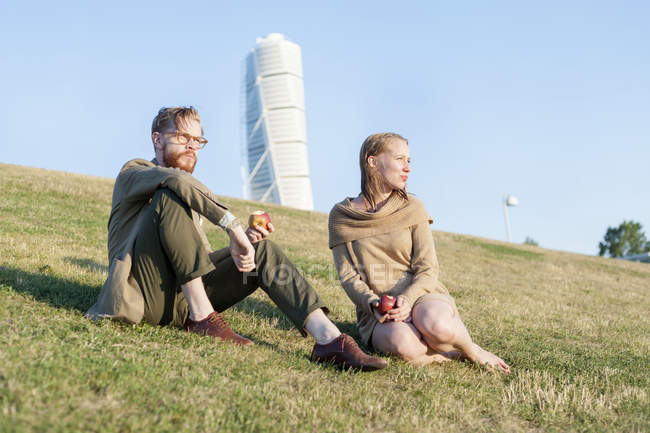 Пары едят яблоки на травянистом холме — стоковое фото