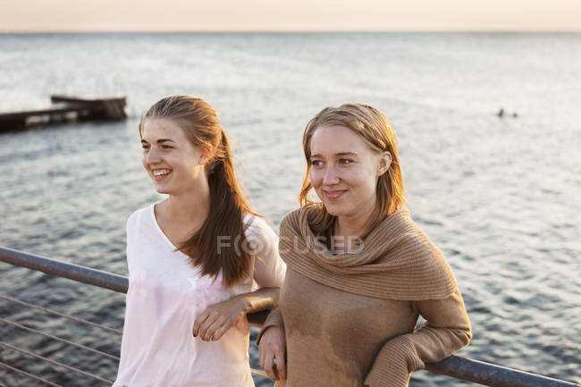 Women leaning on railing by sea — Stock Photo