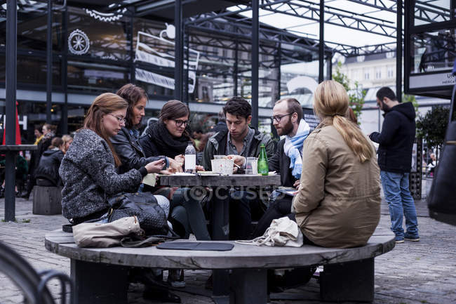 Друзья, сидящие в открытом ресторане — стоковое фото