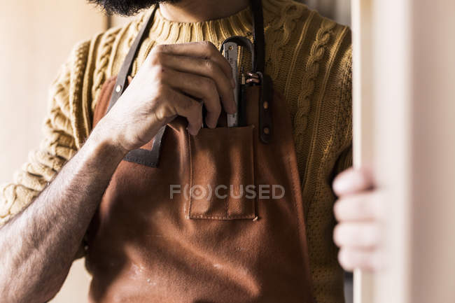 Плотник держит линейку в кармане фартука — стоковое фото