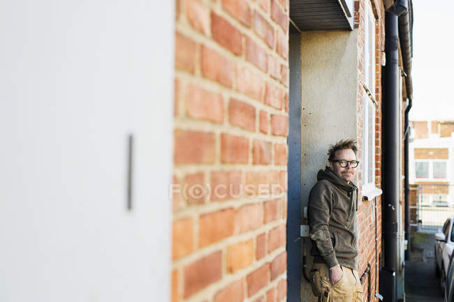 Charpentier appuyé sur un mur de briques — Photo de stock