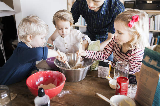 Niños mezclando ingredientes de pan en un tazón - foto de stock