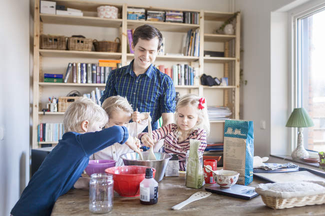 Happy father with children mixing ingredients — Stock Photo