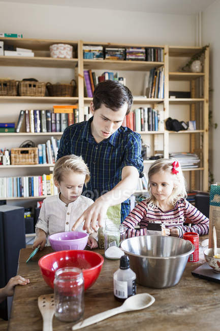 Happy father with children mixing ingredients — Stock Photo