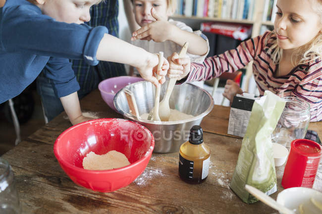 Padre feliz con los niños mezclando ingredientes - foto de stock