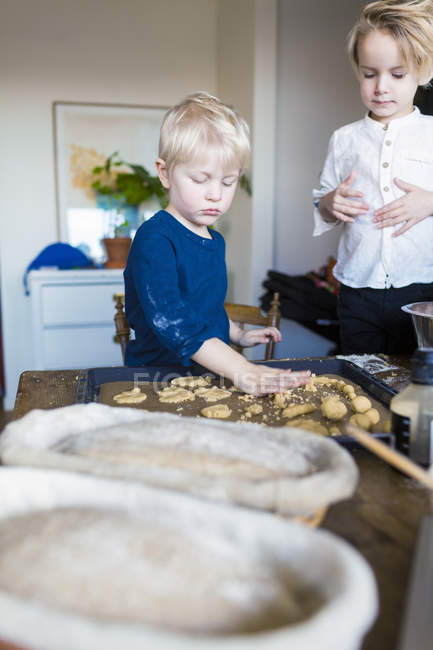 Hermanos horneando galletas en casa - foto de stock