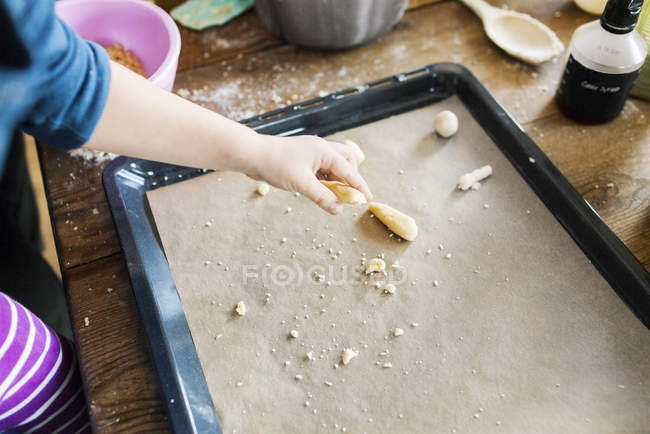 Boy keeping dough on baking sheet — Stock Photo