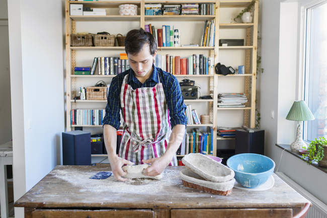 Пекарь месит тесто за столом — стоковое фото