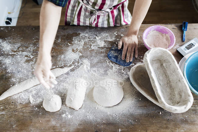 Hand dusting flour on dough in bakery — Stock Photo