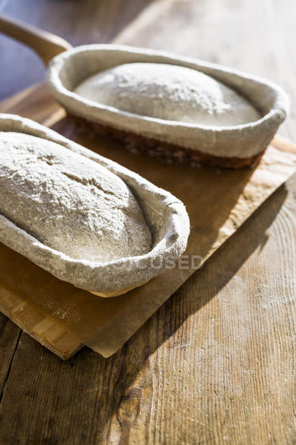 Bread loaves in baskets on chopping board — Stock Photo