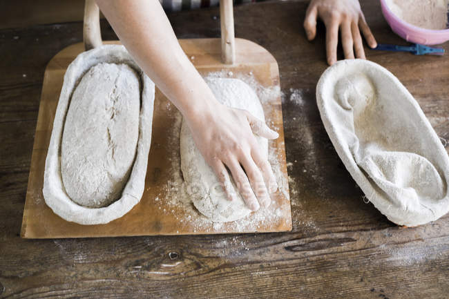Panaderos manos con masa en la mesa - foto de stock