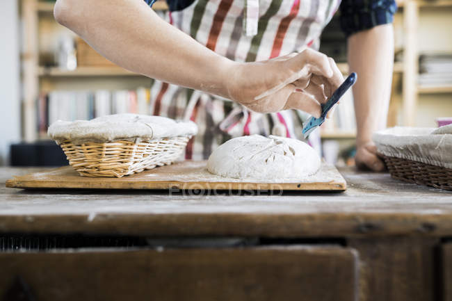 Baker making design on dough — Stock Photo