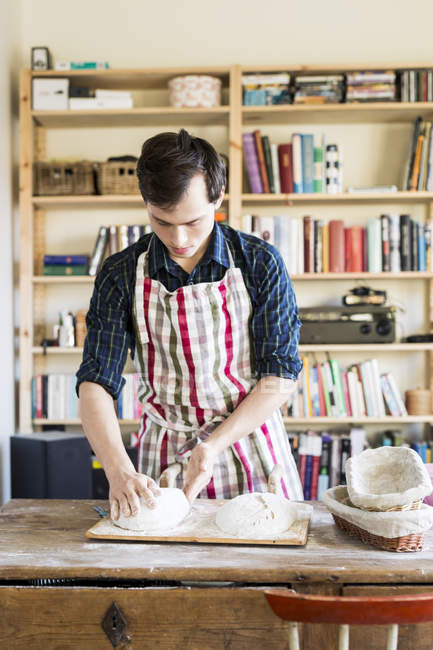 Baker making bread loaf at table — Stock Photo