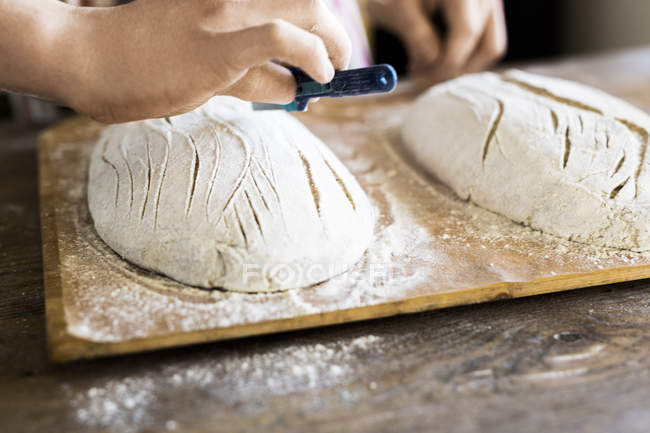 Bakers hands making design on dough — Stock Photo