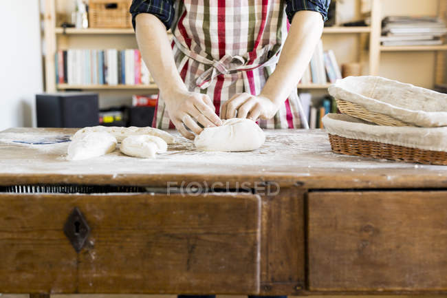 Padeiro amassar massa de farinha à mesa — Fotografia de Stock