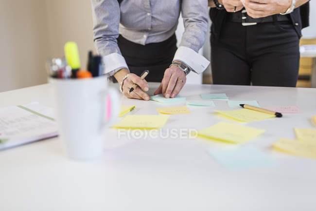 Empresárias preparando lembretes na mesa — Fotografia de Stock