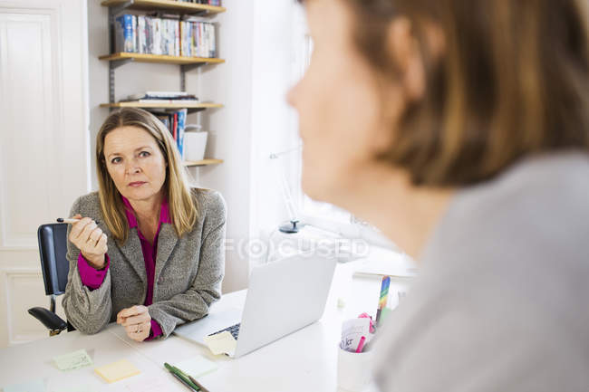 Бізнес-леді спілкуються за офісними столами — стокове фото