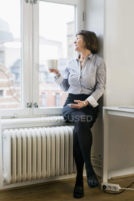 Geschäftsfrau sitzt auf Fensterbank — Stockfoto