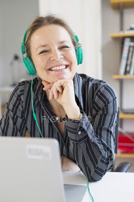 Femme d'affaires portant des écouteurs au bureau — Photo de stock