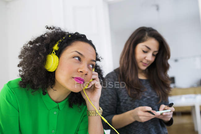 Ділова жінка в навушниках і колега тримає ноту — стокове фото