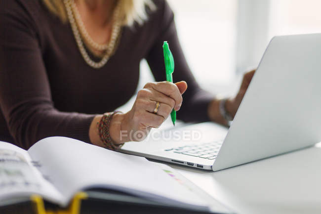 Donna d'affari con penna e laptop in ufficio — Foto stock