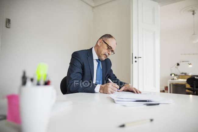 Бизнесмен пишет на документах — стоковое фото