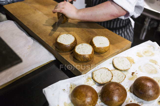 Chef affettare panini al bancone della cucina — Foto stock
