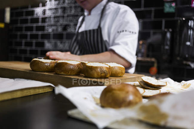 Chef slicing buns at kitchen counter — Stock Photo