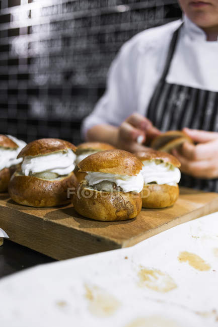 Chef com pães creme na cozinha — Fotografia de Stock