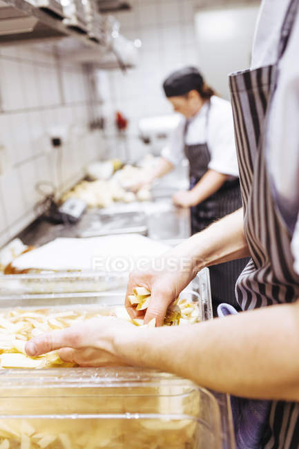 Chef washing raw potato chips — Stock Photo