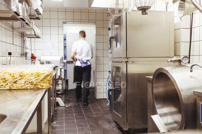 Chef masculino caminando en cocina comercial - foto de stock