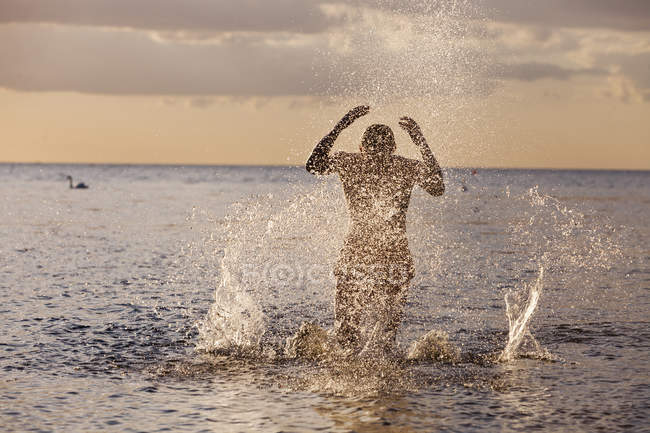 Glücklicher Mann rennt und plätschert Wasser — Stockfoto